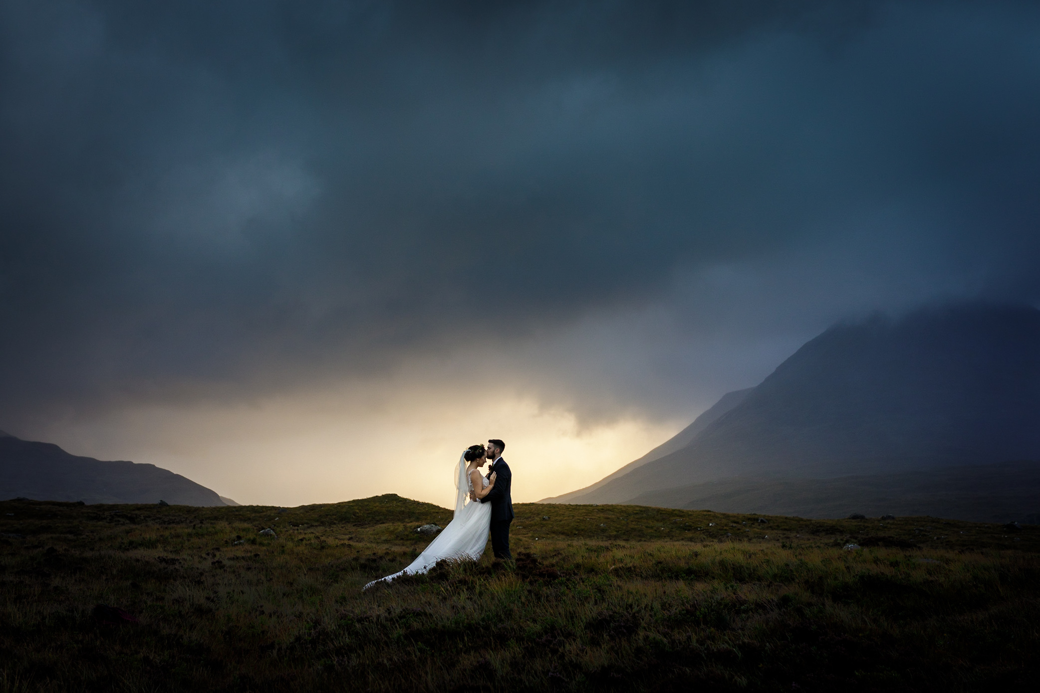 A bride and groom embrace at sunrise after their wedding on Skye